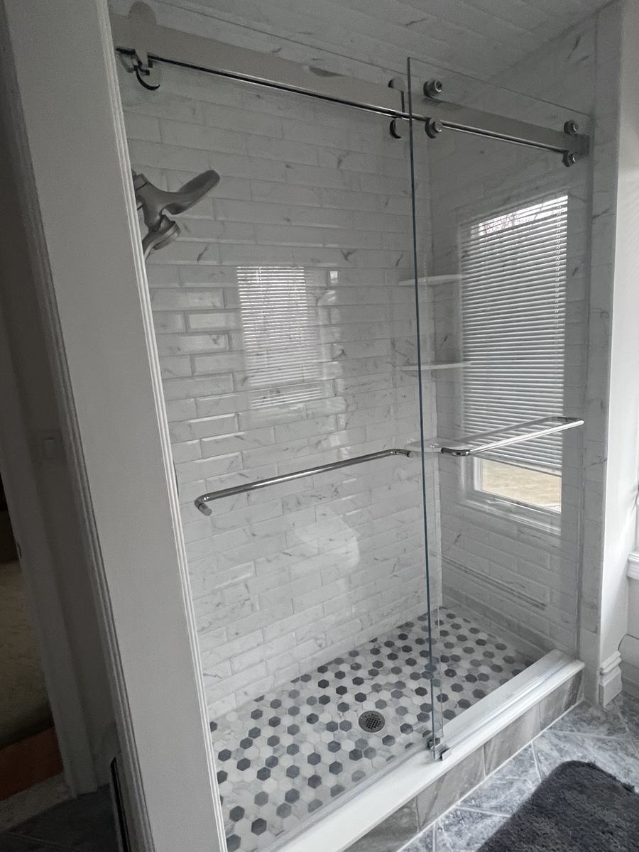 Frameless double sliding shower doors with chrome hardware